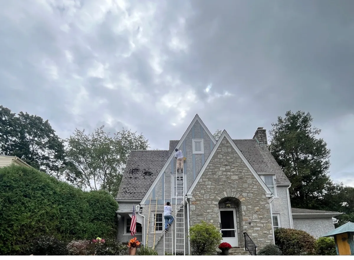 Wide view of exterior painting in progress on a historic stone home